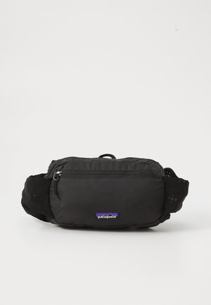 Black fabric waist bag with a zippered compartment, adjustable straps, and highlighted with a small Patagonia logo patch at the front.