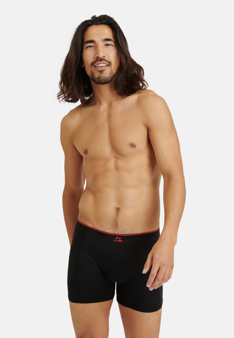 Svarta boxershorts med röd midjeband, gjorda av mjukt material. Kroppsnära design med klassisk skärning och bekväm stretch.