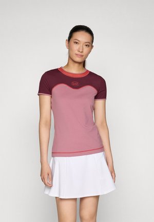Top aderente a maniche corte in rosa chiaro e bordeaux con dettagli rossi, caratterizzato da un design curvo e un logo sul petto. Texture liscia.