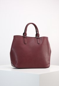 Bordeaux lederen schoudertas met twee bovenhandvatten, gladde textuur en een gestructureerde vorm. Kenmerkt zich door subtiele stiksels en geen zichtbare hardware.