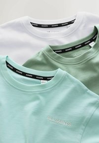 Tri tričká v bielej, mätovo zelenej a jemne zelenej farbe, s okrúhlym výstrihom a čiernymi štítkami "ALLSAINTS" vo vnútri golierov.
