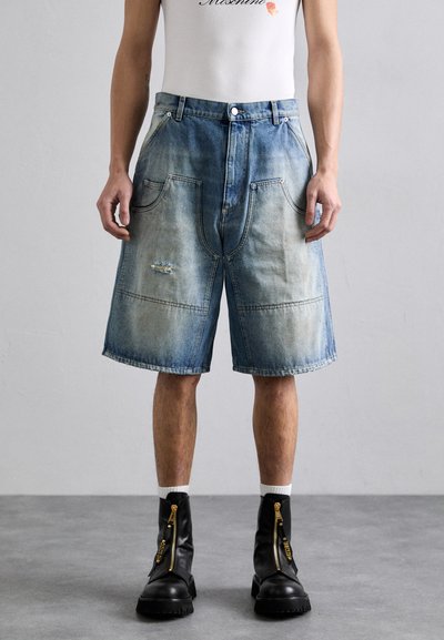 Denimshorts med en falmet blå gradient, der har store lommer, slidte detaljer og en løs pasform. Kombineret med lynlåse sorte støvler.