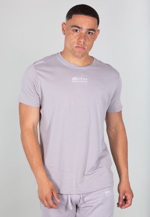 Light gray short-sleeved t-shirt with a crew neck. Features "ALPHA INDUSTRIES" logo in white on the chest. Made of smooth, soft fabric.