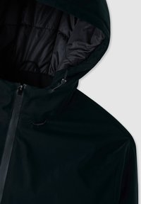 Giubbotto isolante nero con cappuccio, caratterizzato da un esterno liscio e un rivestimento trapuntato. Include una cerniera frontale e cordini regolabili.