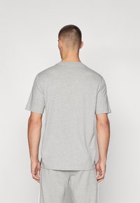 T-shirt en coton gris avec col rond et manches courtes, présentant une coupe décontractée et une texture douce. Aucun détail de design proéminent n'est visible.