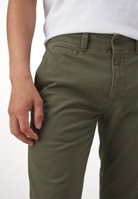 Khaki pants made of soft cotton, featuring a slim fit, side pockets, and a button closure with a textured surface.