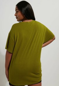 Olivenfarbener, übergroßer T-Shirt aus weichem, glattem Stoff. Mit kurzen Ärmeln und rundem Ausschnitt, fällt bis zur Mitte des Oberschenkels.