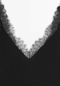 Black garment neckline with delicate floral lace trim featuring fine, fringed edges in a V-shape design.