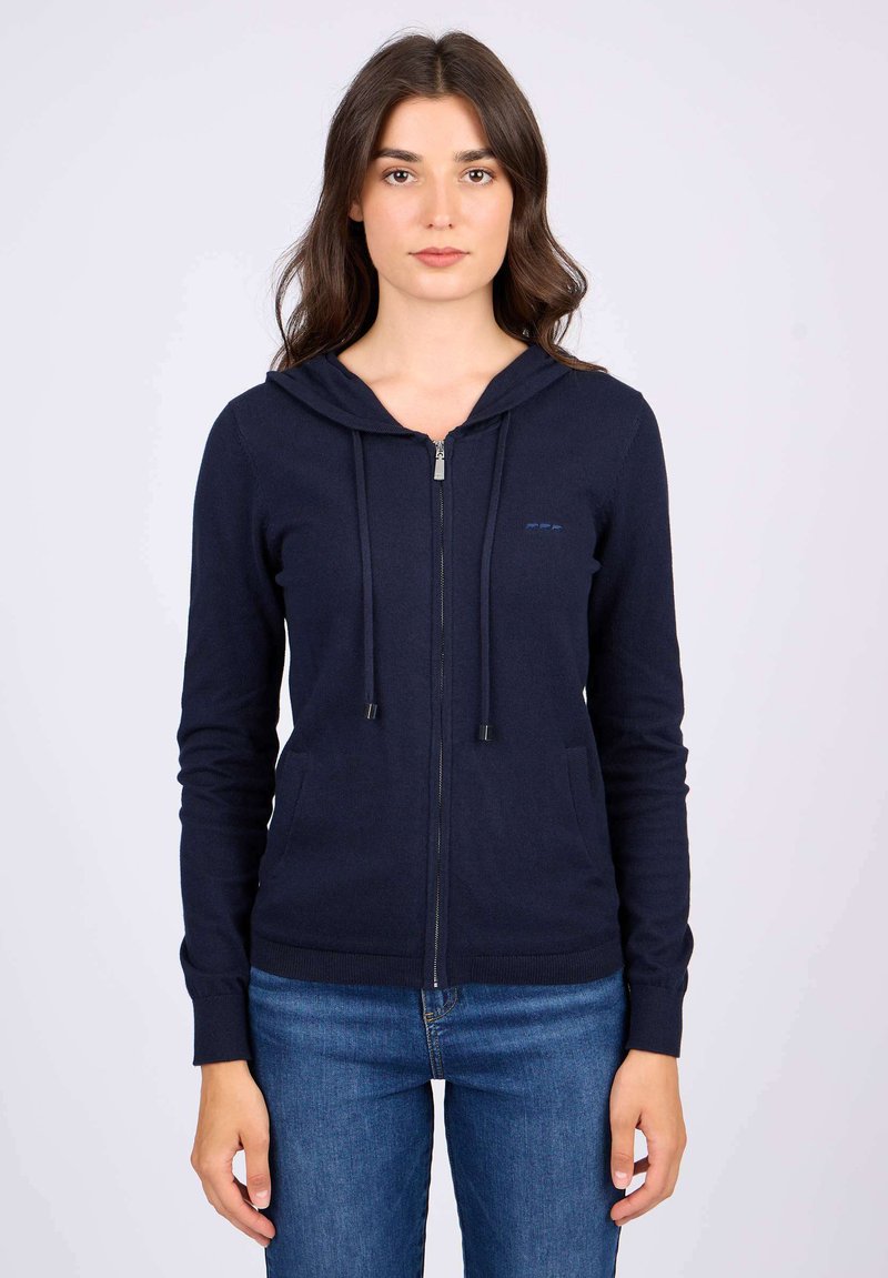 Veste à capuche zippée marine en tissu doux, dotée d'une capuche avec cordon de serrage, de poches avant et de poignets côtelés. Design minimaliste avec un logo discret.