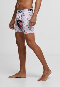 Vita boxershorts med en stor röd hajgrafik, abstrakta mönster och en svart märkeslinning. Mjuk tygstil med en åtsittande design.