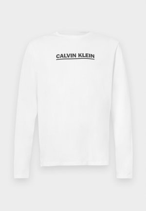 Biela košeľa s dlhým rukávom vyrobená z bavlny, s čiernym logom "CALVIN KLEIN" naprieč hrudníkom a okrúhlym výstrihom. Hladká textúra.