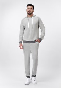Herre loungewear-sæt i lys grå tekstureret stof; med hætte, hvide snore, ribbede manchetter og kontrasterende mørke grå accenter.