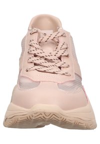 Zapatilla deportiva rosa con parte superior sintética suave, paneles de malla y suela de goma texturizada. Presenta una puntera redondeada y cordones en contraste.
