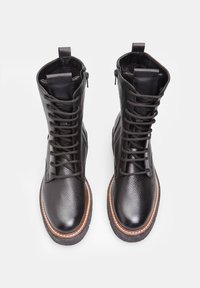 Botas de cuero negras con cordones que presentan un acabado texturizado, punta redonda, suela contrastante con acentos marrones y altura hasta el tobillo para mayor soporte.