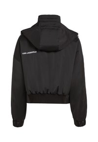 Must mustär kõrge kraega jakk sujuvast kangast, millel on kapuuts, elastne allserv ja soonikud käiste otstes. Seljas on valge kirjatükk "KARL LAGERFELD".