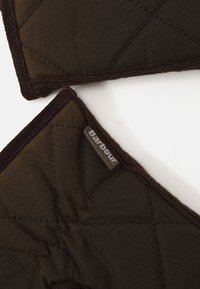 Brown quilted cotton pot holder with dark brown binding. Features visible stitching and a label on one corner. Measures about 20 cm.