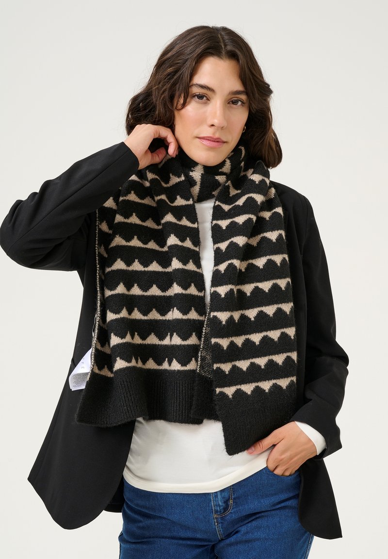 Sciarpa nera e beige con un motivo a zigzag, realizzata in morbido tessuto, con un bordo a costine su entrambi i lati.