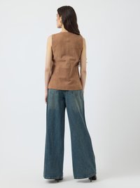 Top din suede maro fără mâneci, cu talie ajustată, asortat cu blugi din denim albastru cu picioare largi. Design minimalist, textură moale, fără modele vizibile.