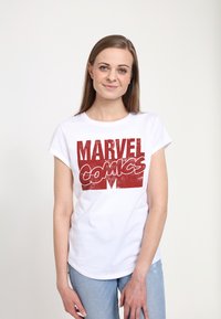Hvid bomulds T-shirt med opfoldede ærmer, der har et slidt rødt grafisk print af "MARVEL Comics" foran. Casual pasform, enkelt design.