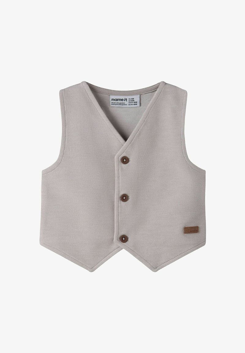 Grijze gebreide spencer met een V-hals, drie bruine knopen en een gestikt bruin label. Heeft een gestructureerde stof en een puntige zoom.