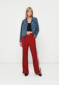 Jeanjacka, svart crop top, röda vida byxor med sidostripes och svarta spetsiga klackar. Slätt tyg och avslappnad design.