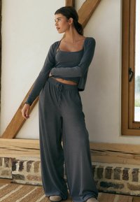 Gray loungewear set featuring a cropped top with scalloped edges and wide-leg pants with an elastic waistband and drawstring. Soft texture.