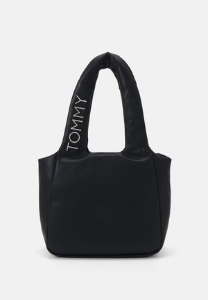 Schwarze gepolsterte Handtasche mit zwei großen Griffen, mit dem auf den Griffen geprägten und gedruckten Text "Tommy Jeans".