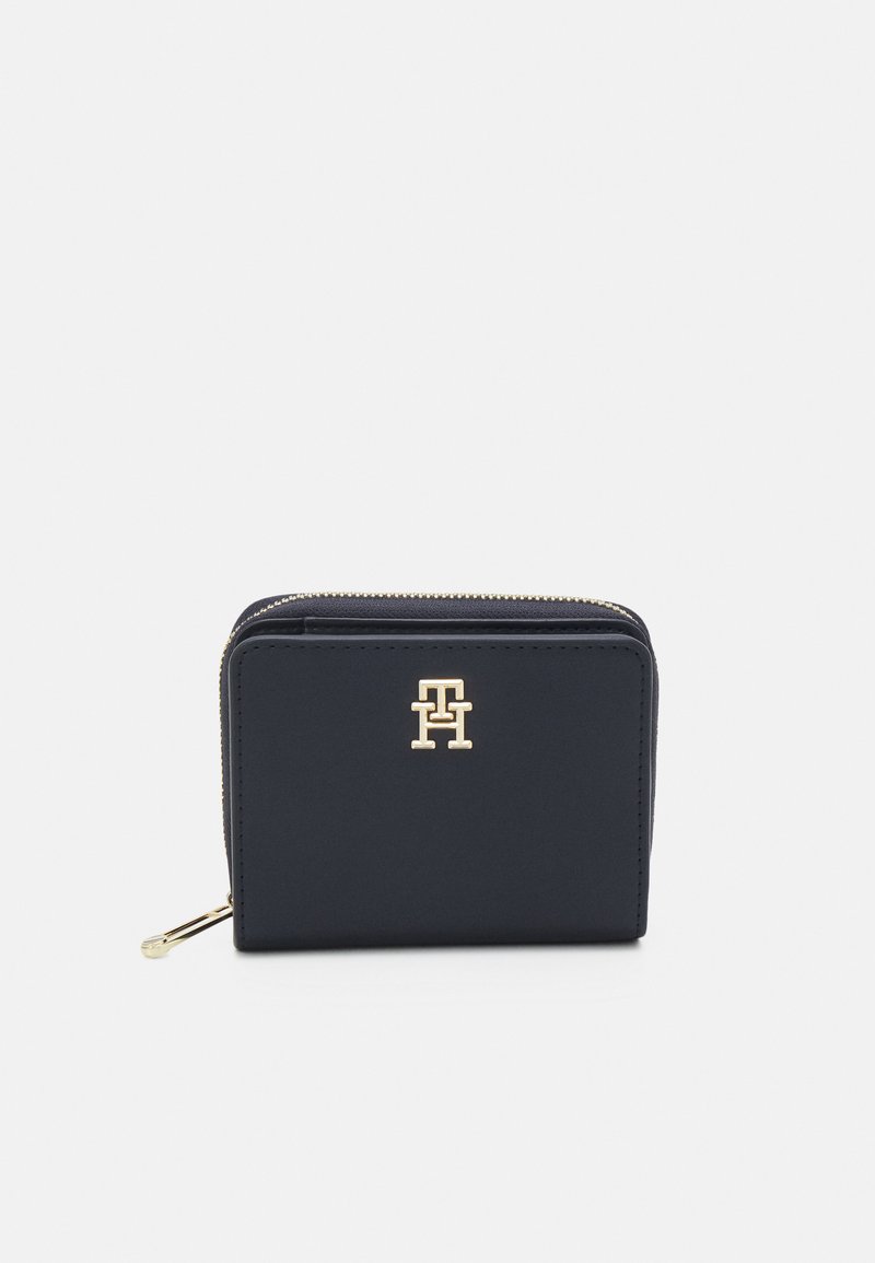 Portafoglio blu navy realizzato in materiale liscio, con un logo dorato sul fronte e una chiusura zip sicura. Design rettangolare compatto.