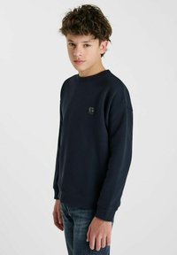 Marineblauwe sweatshirt van zacht materiaal, met een ronde hals en geribbelde mouwen. Kleine logo patch op de borst, ontworpen voor een comfortabele pasvorm.
