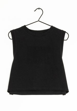 Top corto negro sin mangas con escote redondeado en una percha de metal negra, fondo liso.