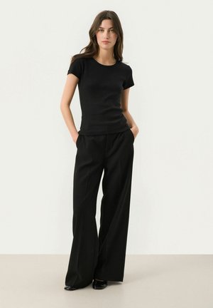 Top negro de manga corta con textura acanalada combinado con pantalones de pierna ancha de talle alto en negro; tejido elegante con una textura suave.