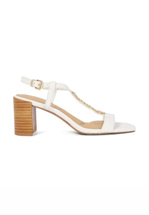 Sandales blanches à talons avec une lanière texturée et un talon bloc en bois. Présentent un design à bride en T et un accent de chaîne métallique.