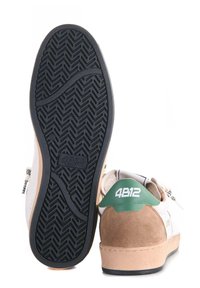 Sneaker bianco con tacco in suede marrone, accentuato da verde sul retro e suola in gomma nera testurizzata con motivo a zigzag.