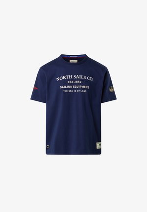 T-shirt in cotone blu navy con colletto a girocollo, caratterizzato da grafiche in testo bianco, dettagli rossi sulle maniche e una toppa con logo sull'orlo.