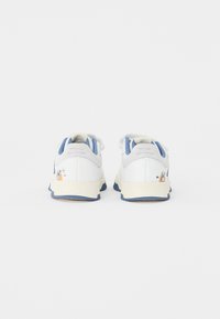 Białe trampki z niebieskimi akcentami, wyściełanym siateczkowym językiem, lekko teksturowaną cholewką, gumową podeszwą oraz dekoracyjną grafiką po zewnętrznej stronie.
