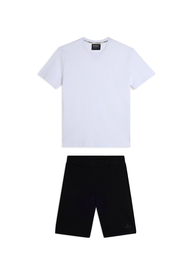 Camiseta blanca de manga corta y escote en V combinada con pantalones cortos negros hasta la rodilla. La camiseta tiene una etiqueta con el logotipo y los pantalones cortos cuentan con un cinturón elástico.