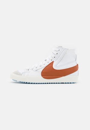 High-top sneakers with a white leather upper, orange leather accents, grey toe cap, and a textured blue rubber sole. Lace-up design.