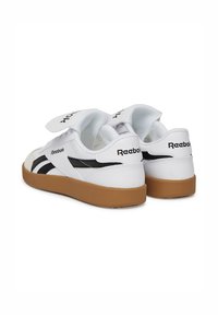 Biele kožené tenisky s čiernymi prúžkami po stranách a logom Reebok. Obsahujú suchý zips a gumenú podrážku. Textúrovaný povrch pre lepšiu priľnavosť.