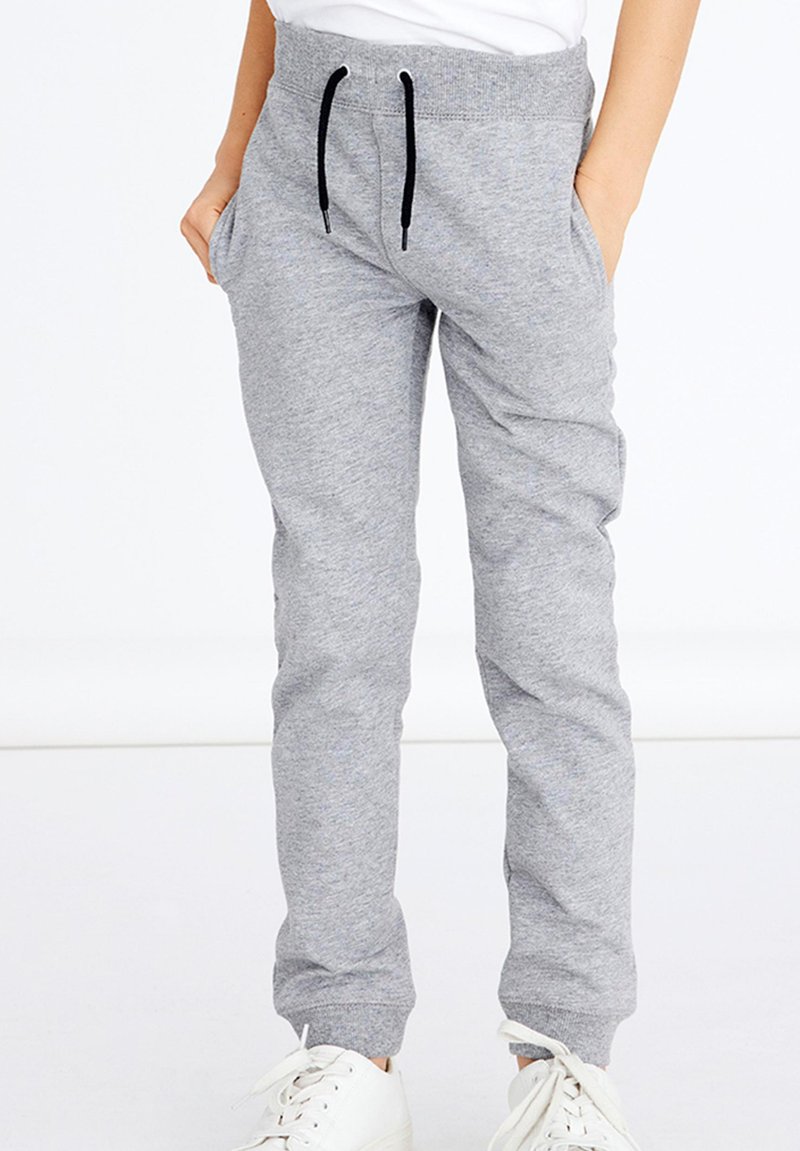 Pantalons de survêtement gris avec une taille élastique, des cordons de serrage noirs, deux poches latérales et des chevilles fuselées. Fabriqués en matériau doux et extensible.