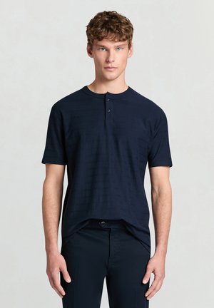 Marineblaues Henley-Shirt mit kurzen Ärmeln aus strukturiertem Stoff, mit rundem Ausschnitt und drei Frontknöpfen, in lockerer Passform.