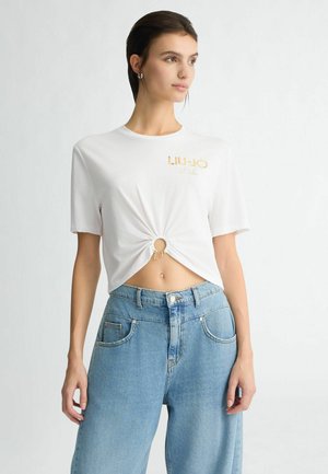 White short-sleeve t-shirt with a knotted front detail and "LIU-JO" logo in gold. Paired with high-waisted light blue wide-leg jeans.