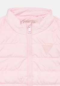 Ροζ ανοιχτό ροζ μπουφάν με ψηλό γιακά, κλείσιμο με φερμουάρ, καπιτονέ υφή και ψηλό τριγωνικό λογότυπο στην αριστερή πλευρά.