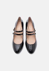 Črne lakirane Mary Jane čevlje z dvema nastavljivima trakoma, koničastimi prsti in oblazinjeni podplat z perforiranimi podrobnostmi.