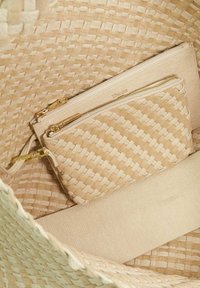 Geweven beige tote met een verwijderbare ritszak. Heeft een textuurpatroon, een gladde voering en accenten van goudkleurig hardware.