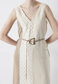Vestido con escote en V, paneles beige y blanco roto, lado texturizado blanco roto y un cinturón marrón con hebilla en forma de corazón.