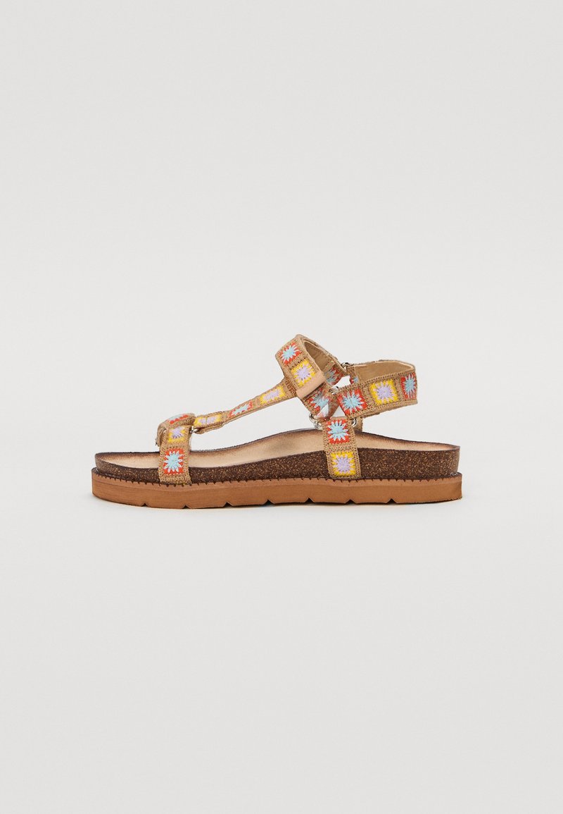 Sandales marron avec des bretelles brodées colorées, dotées d'une semelle plate et d'une sangle réglable à la cheville. Semelle intérieure texturée pour le confort.