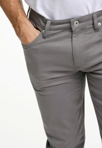 Grijze katoenen broek met een slim fit, voorzien van een knoopsluiting, zijzakken en een gladde textuur.