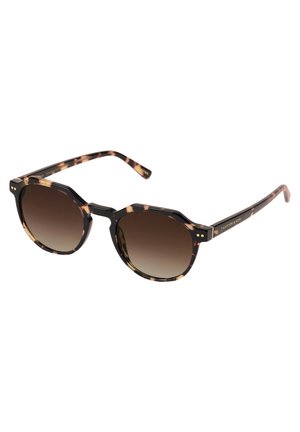 Lunettes de soleil en écaille de tortue avec une monture hexagonale, verres dégradés marron et accents dorés sur les branches. Fini texturé sur la monture.