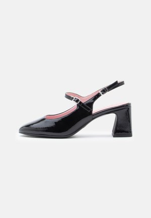 Black patent leather slingback heels with pointed toe, pink interior, and a chunky heel. Features an adjustable ankle strap with buckle.