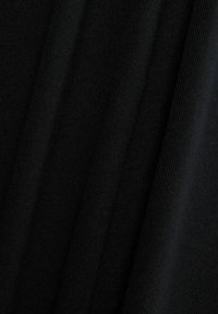 Mustasta kankaasta, jossa on pehmeä, teksturoitu neulos. Pliseeraukset luovat syvyyttä, korostaen tasaista pintaa, jossa väri ja kuvio ovat yhtenäisiä koko matkalta.